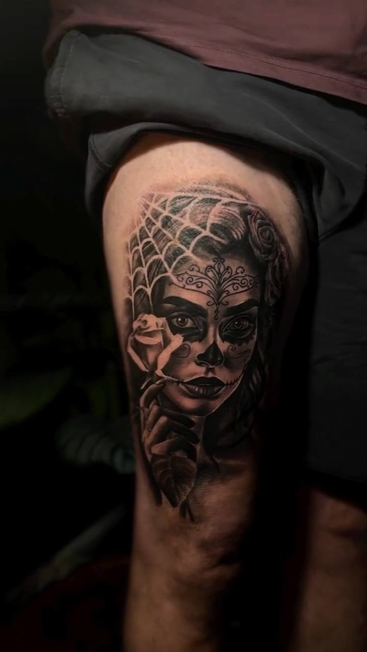 Woman with sugar skull face paint on a thigh