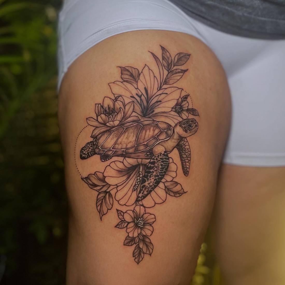 Black and grey turtle with flowers on a thigh