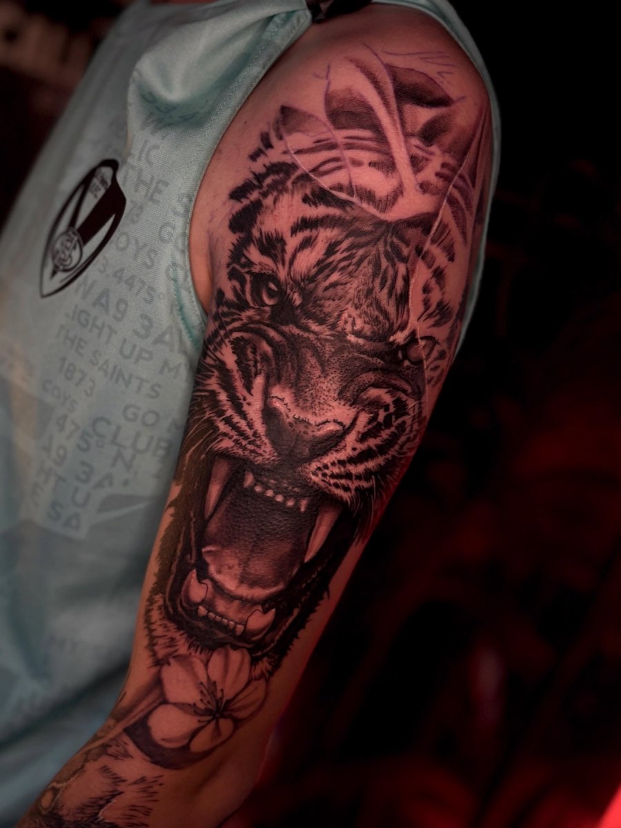 Black and grey tiger tattoo covering an upper arm